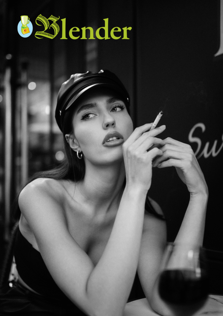 Portrait en noir et blanc d'une jeune femme élégante, portant un chapeau de style fashion, tenant une cigarette et posant avec une expression pensante, un verre de vin visible au premier plan.