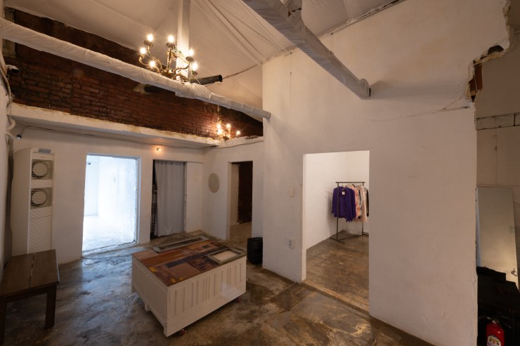 Intérieur du 09Salon à Séoul, montrant un espace lumineux avec des murs blancs et un plafond en briques, comprenant un meuble central et des vêtements accrochés sur un portant.