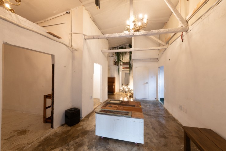 Intérieur minimaliste de 09Salon, un espace hybride à Séoul, avec un sol en béton, des murs blancs et une ambiance accueillante. Un grand chandelier pend au plafond, et une table centrale est visible.