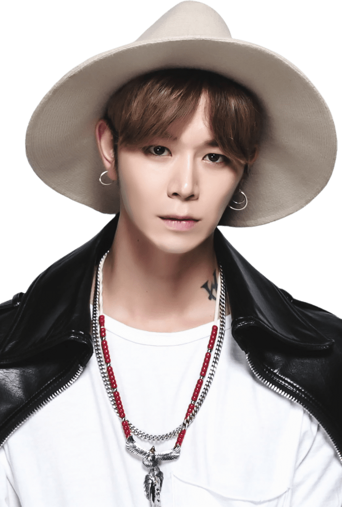 A young man wearing a wide-brimmed hat, leather jacket, and layered necklaces, gazing directly at the camera.